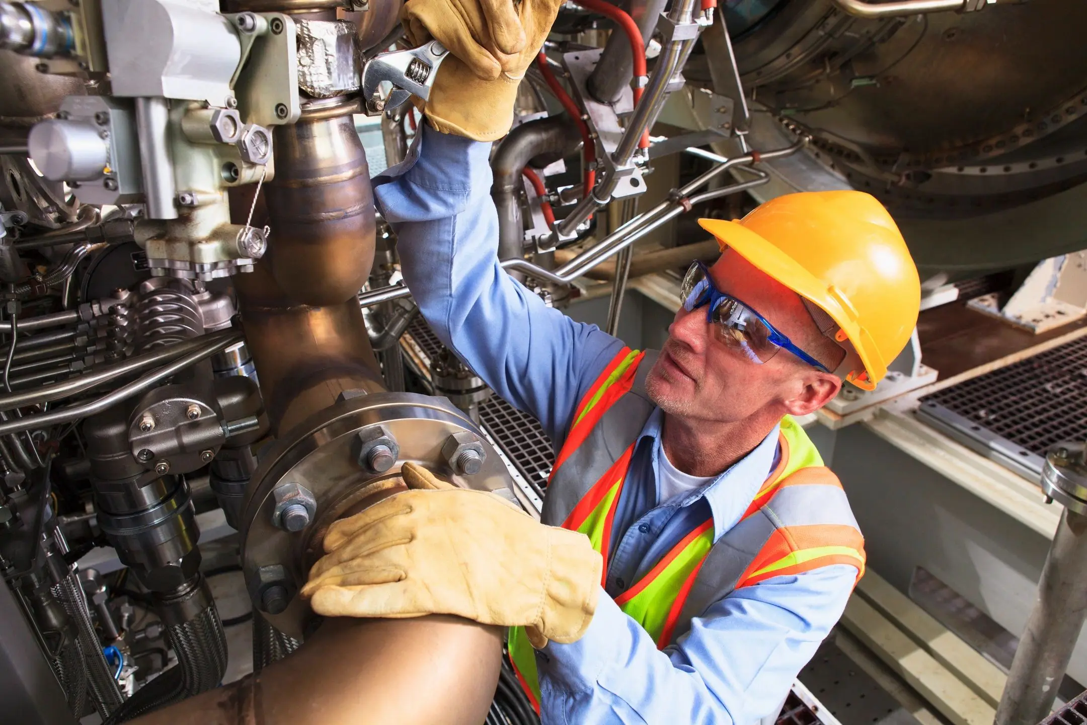Engineer inspecting machinery, wearing safety gear.