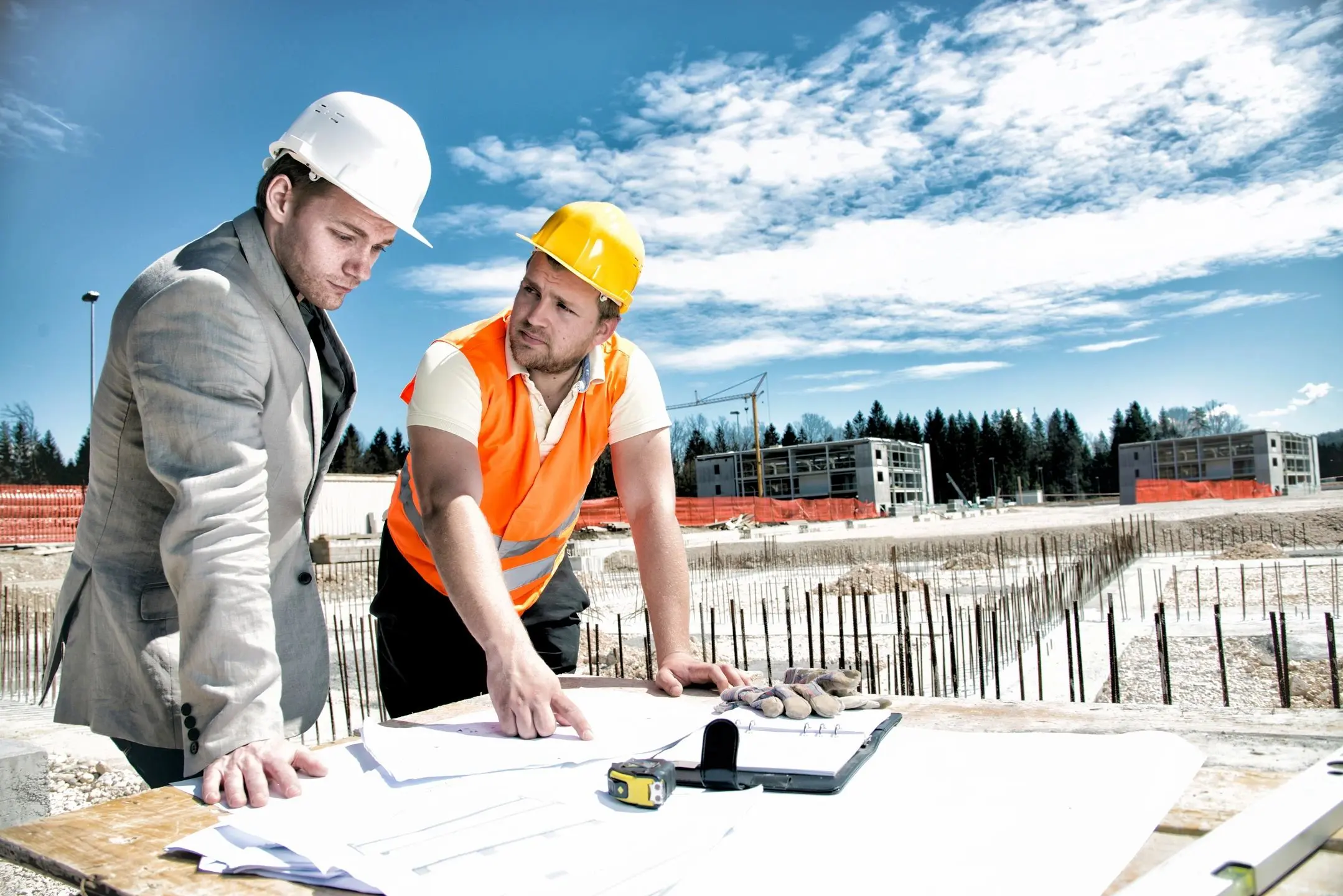 Construction workers reviewing building plans on site.